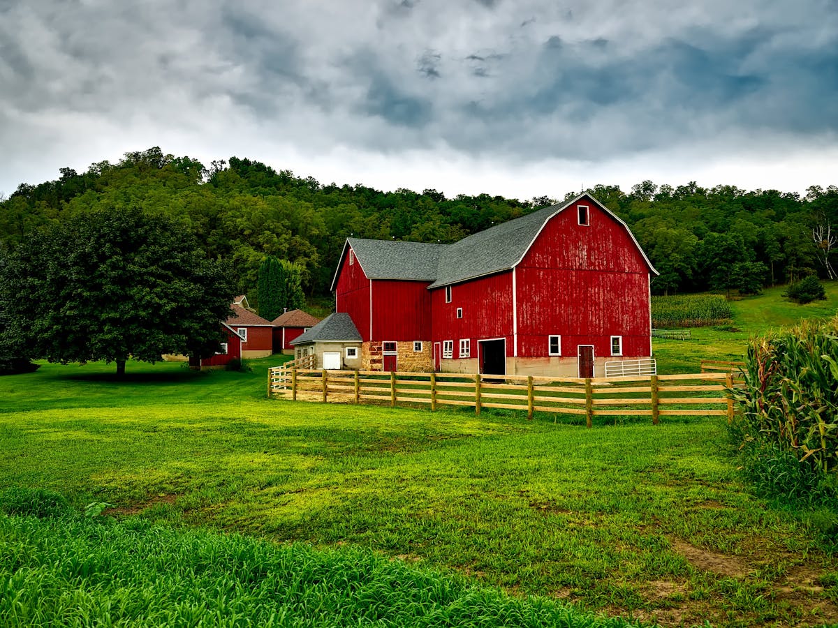A classic red pole barn on farmland with metal roofing and fenced pasture — one of the most recognizable building styles in rural America.